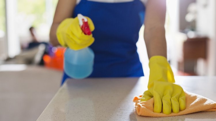 Professional house cleaner sanitizing a countertop in a Colorado home.